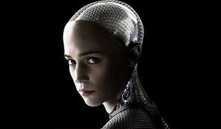 An image of Ava from the movie Ex Machina from the shoulders up. She looks into the camera. She is a bald, silver robot with a feminine, human-looking face.